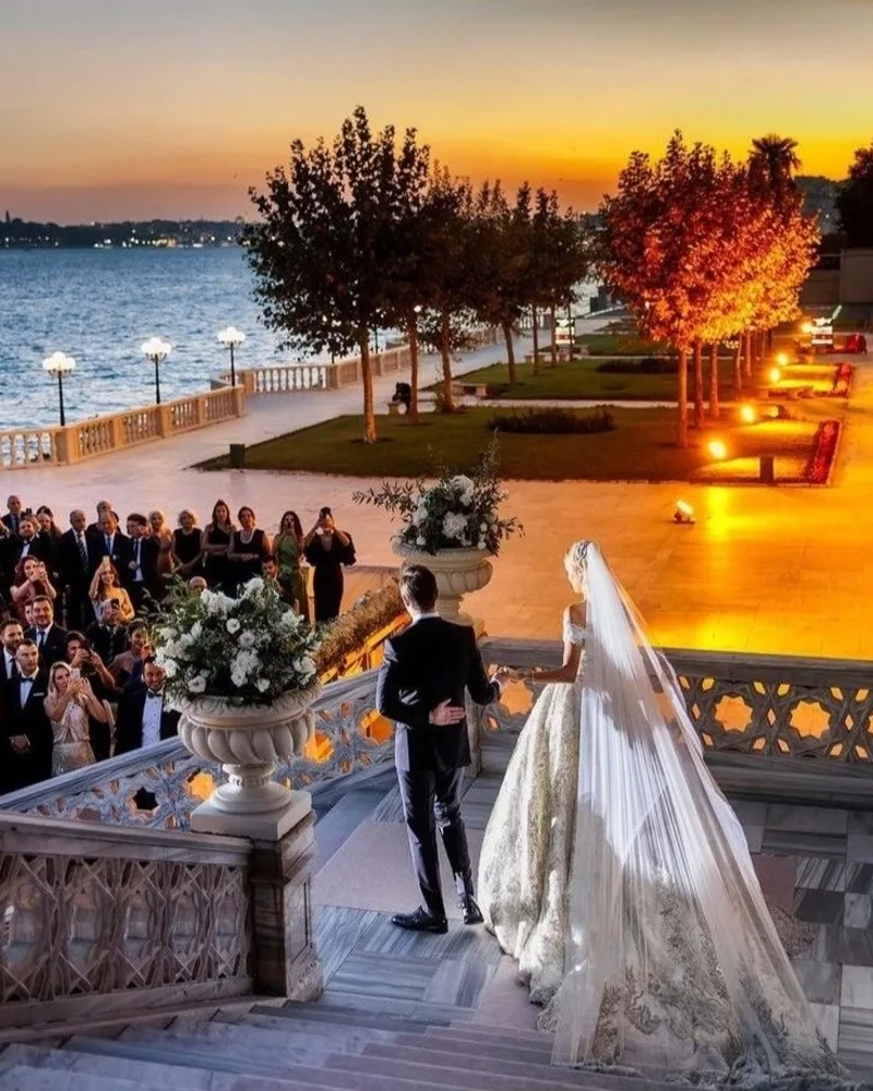 Gün batımında merdivenden inen gelin ve damadı alkışlayan davetliler