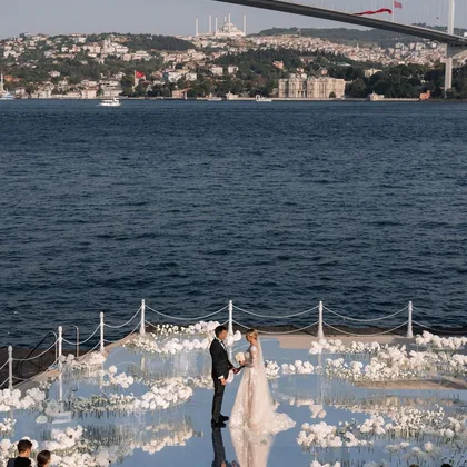Boğaz kıyısında beyaz çiçekli tören yolunda gelin ve damat